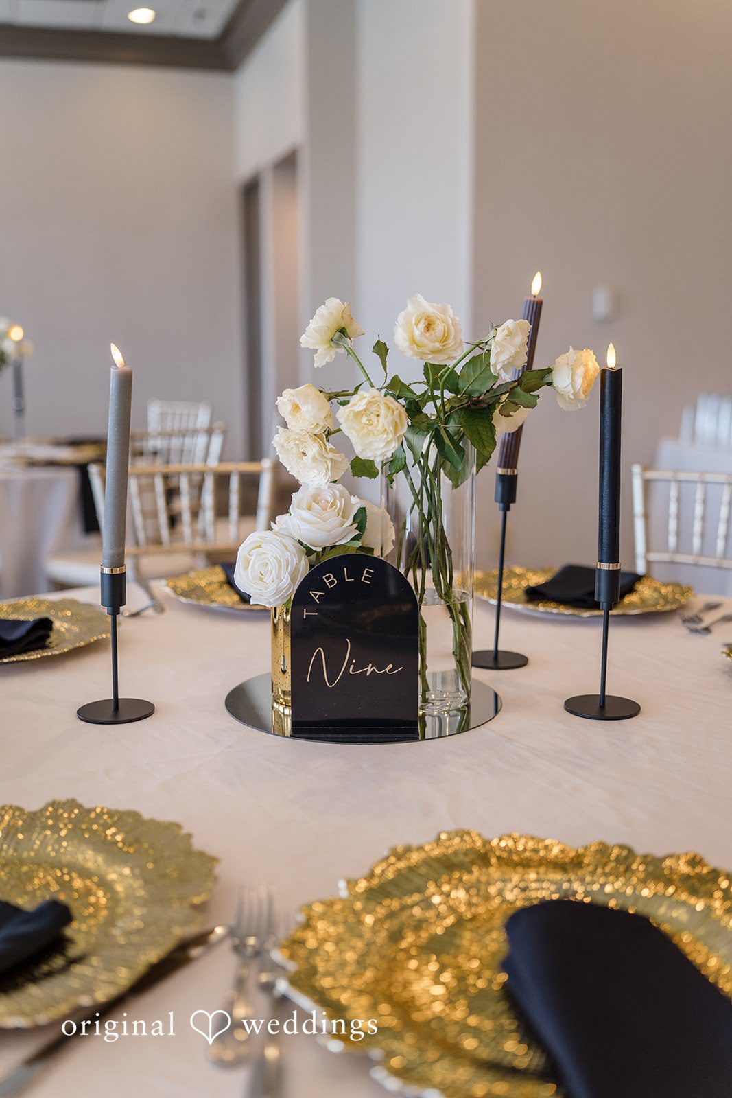 Nicholas + Nisha Elegant wedding reception table decorated with candles, floral arrangements, and golden charger plates.