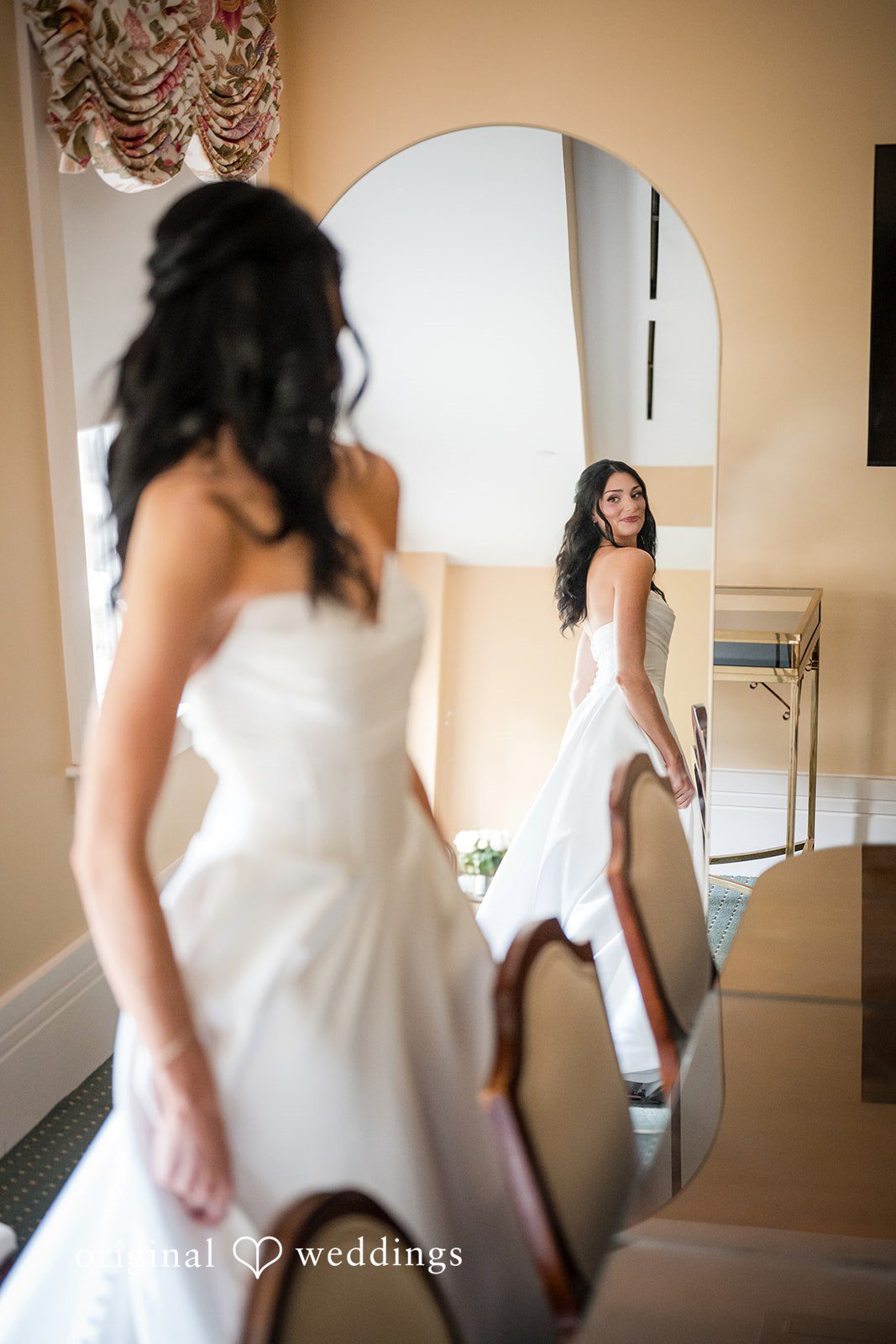 Macy + Nolan A bride in a white wedding gown getting ready while looking at her reflection.