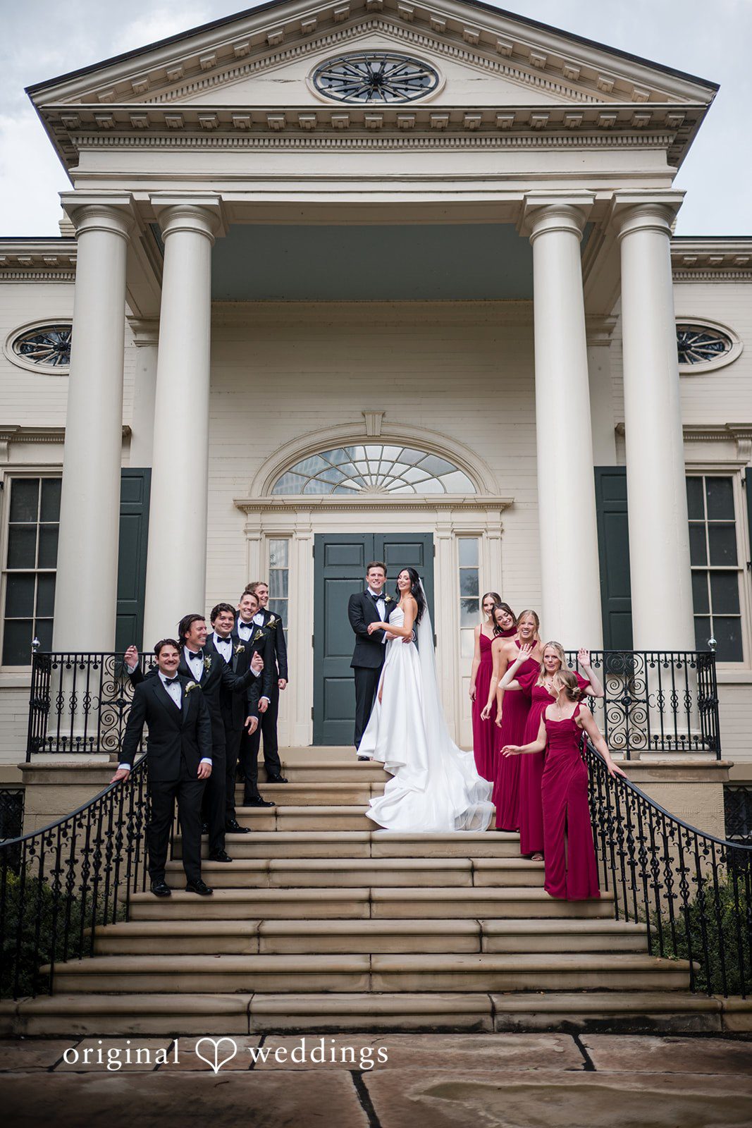 Macy + Nolan A wedding party gathered on the front steps of a grand columned building.