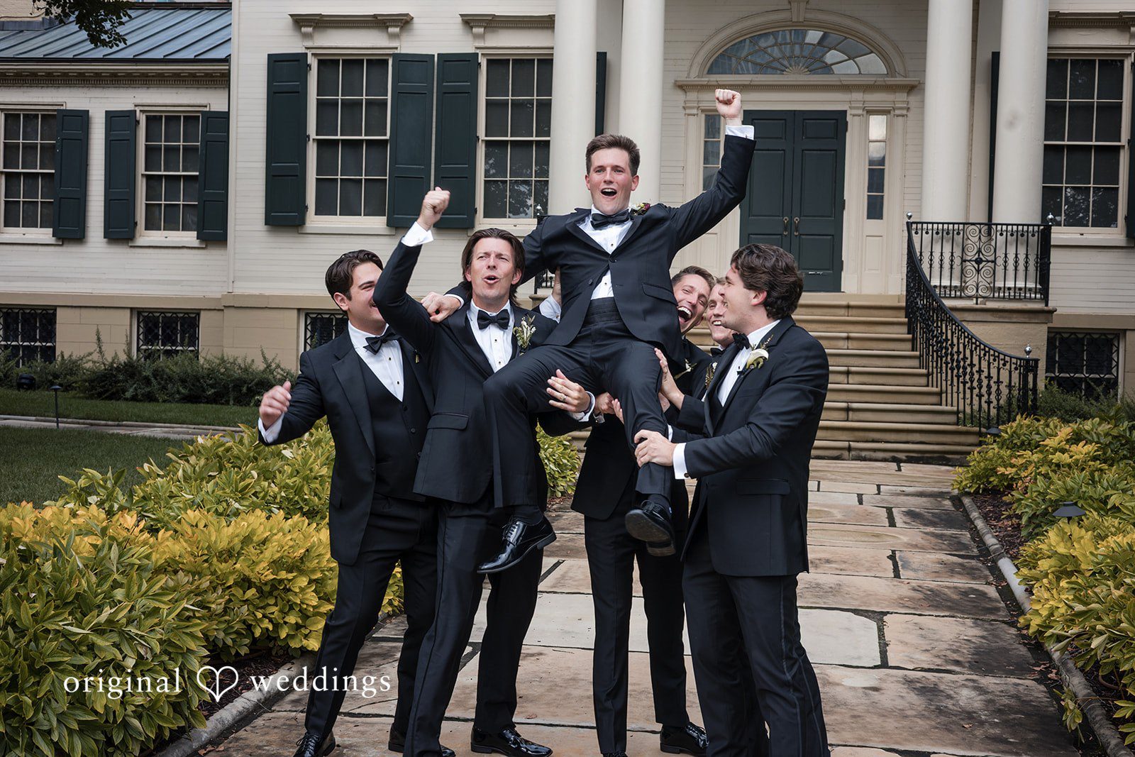 Macy + Nolan Groomsmen in black tuxedos celebrating together.