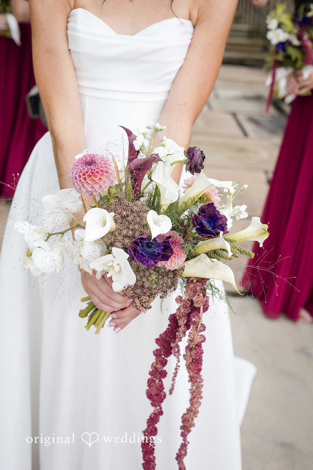Macy + Nolan A close-up shot focusing on a wedding bouquet held next to a burgundy dress.