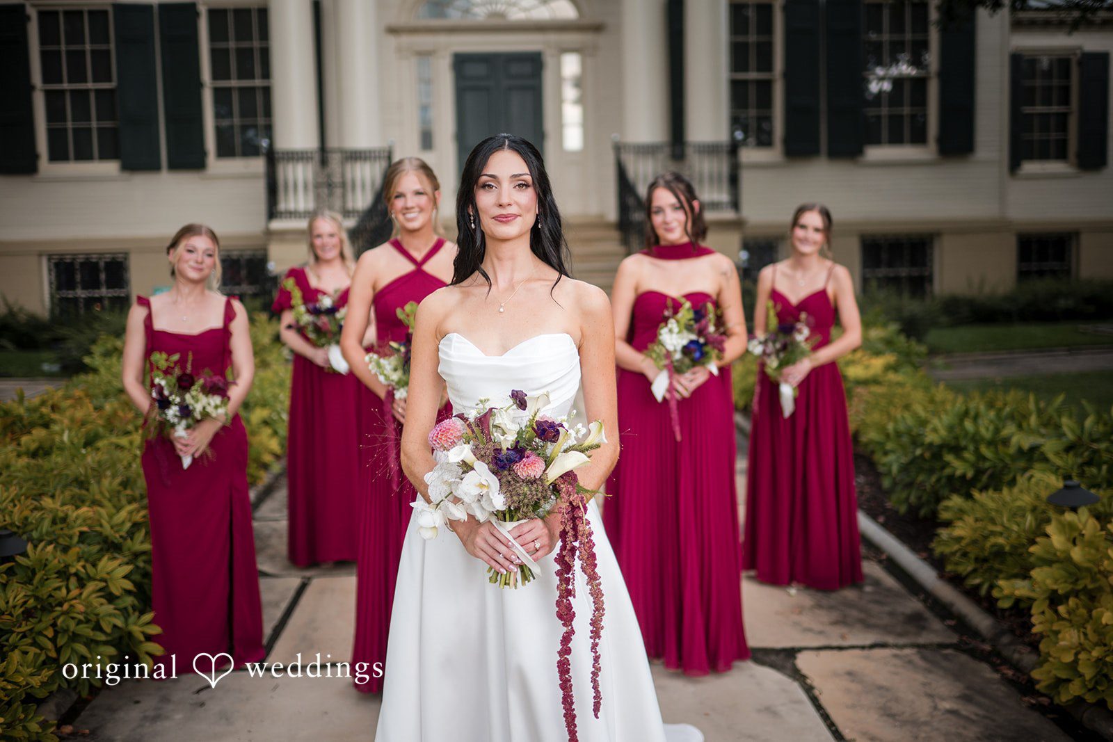 Macy + Nolan A bride standing with her bridesmaids who are wearing burgundy dresses.