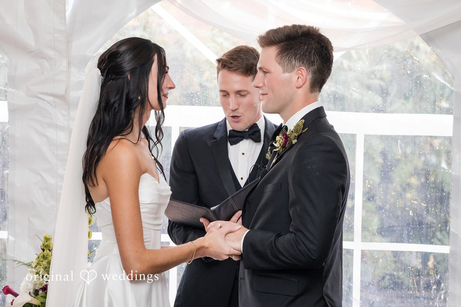Macy + Nolan A bride and groom holding hands during their wedding ceremony.