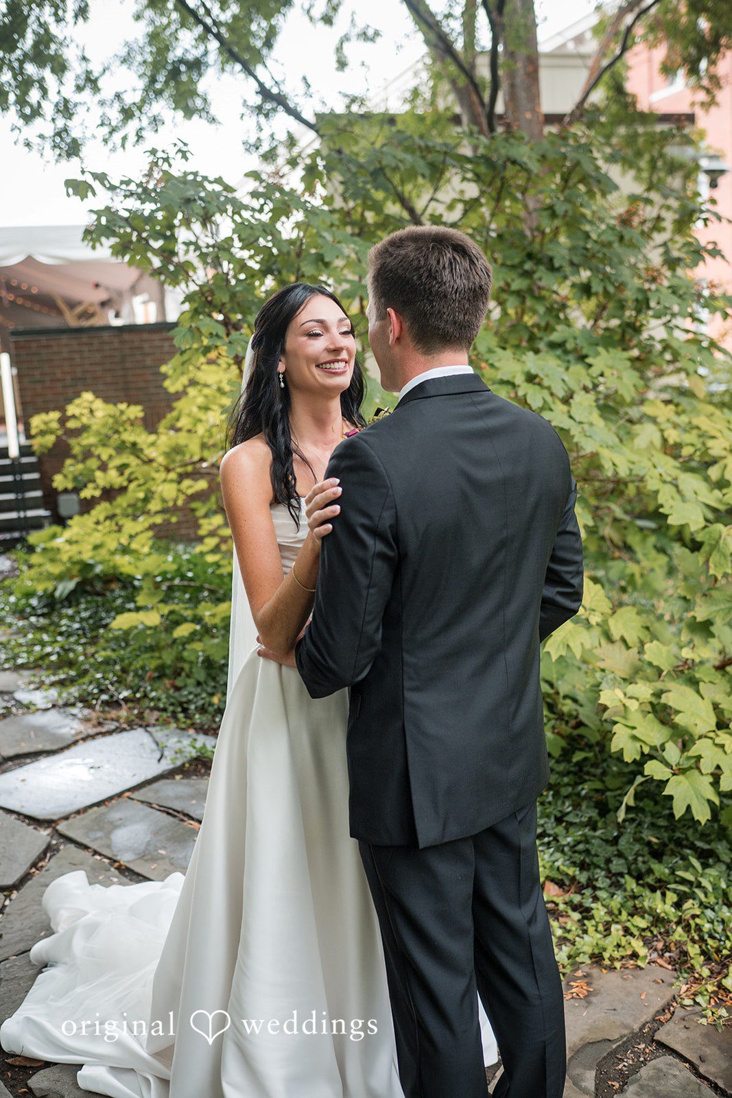 Macy + Nolan A bride and groom standing together against a background of green foliage.