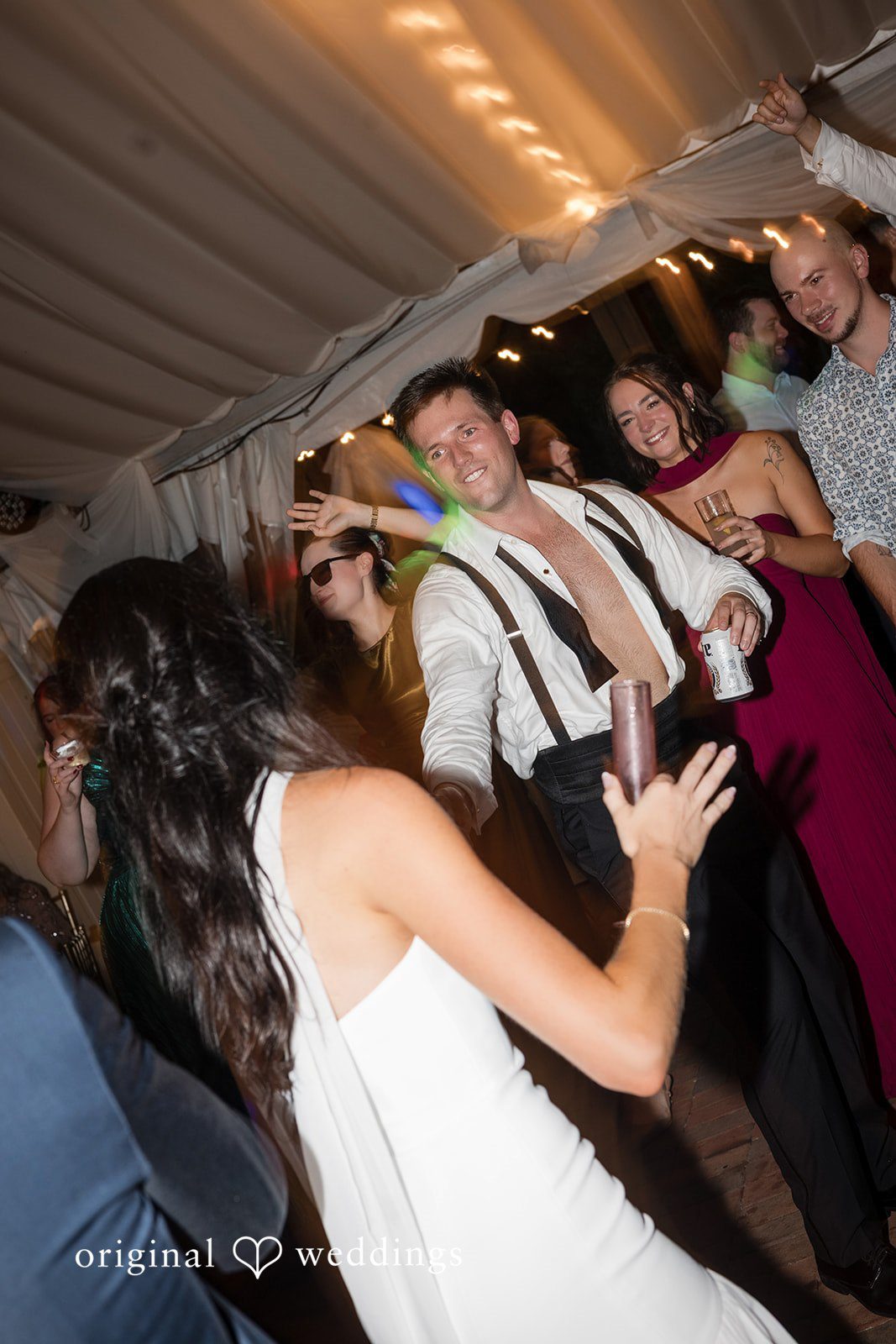 Macy + Nolan A bride dancing energetically on the dance floor surrounded by wedding guests.