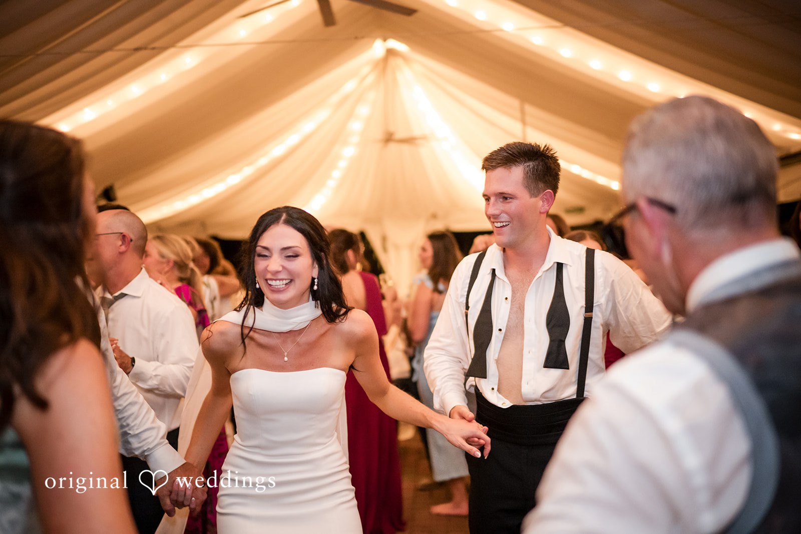 Macy + Nolan Wedding guests dancing and celebrating together under tent lighting.