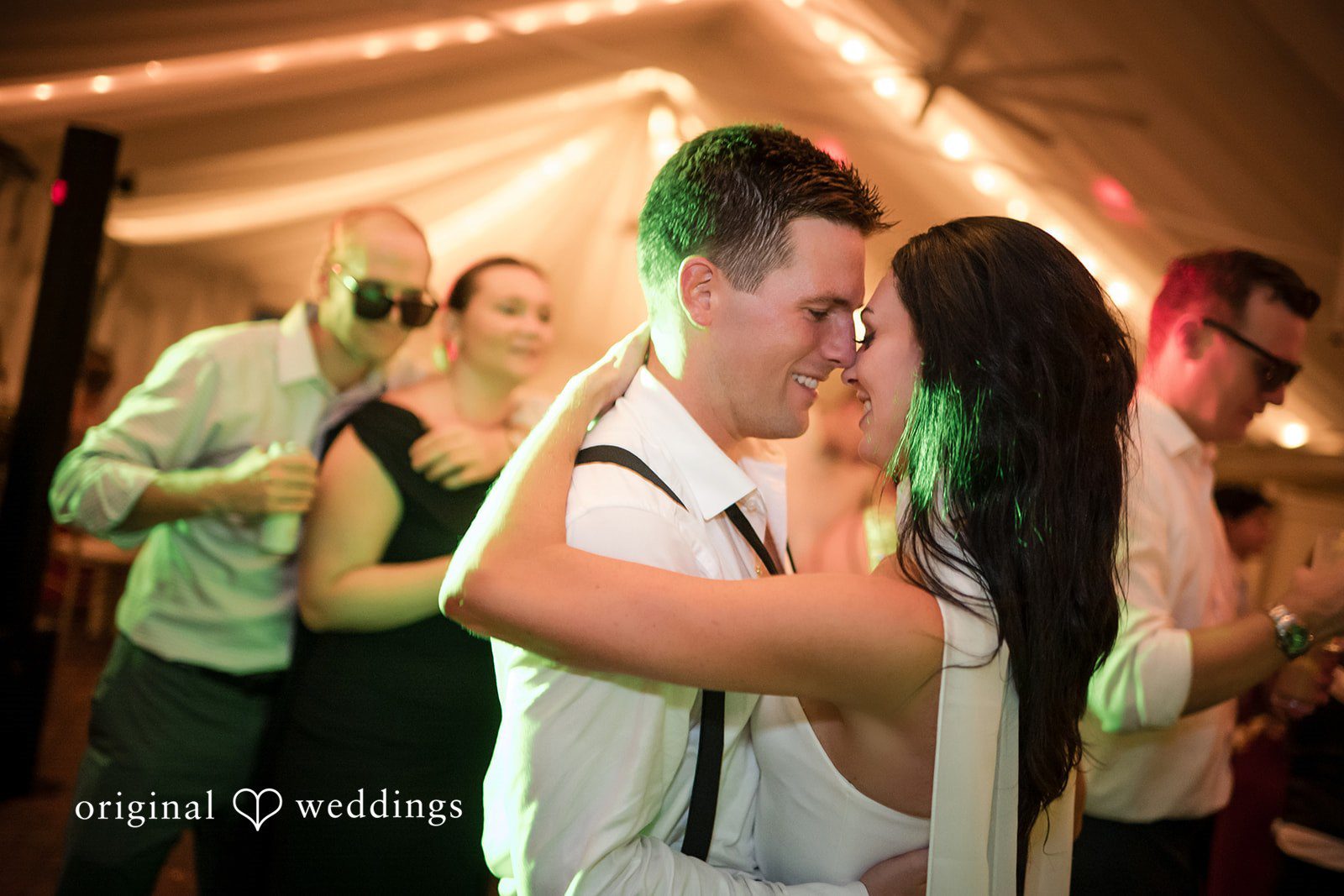 Macy + Nolan A bride and groom sharing an intimate embrace on a dimly lit dance floor.