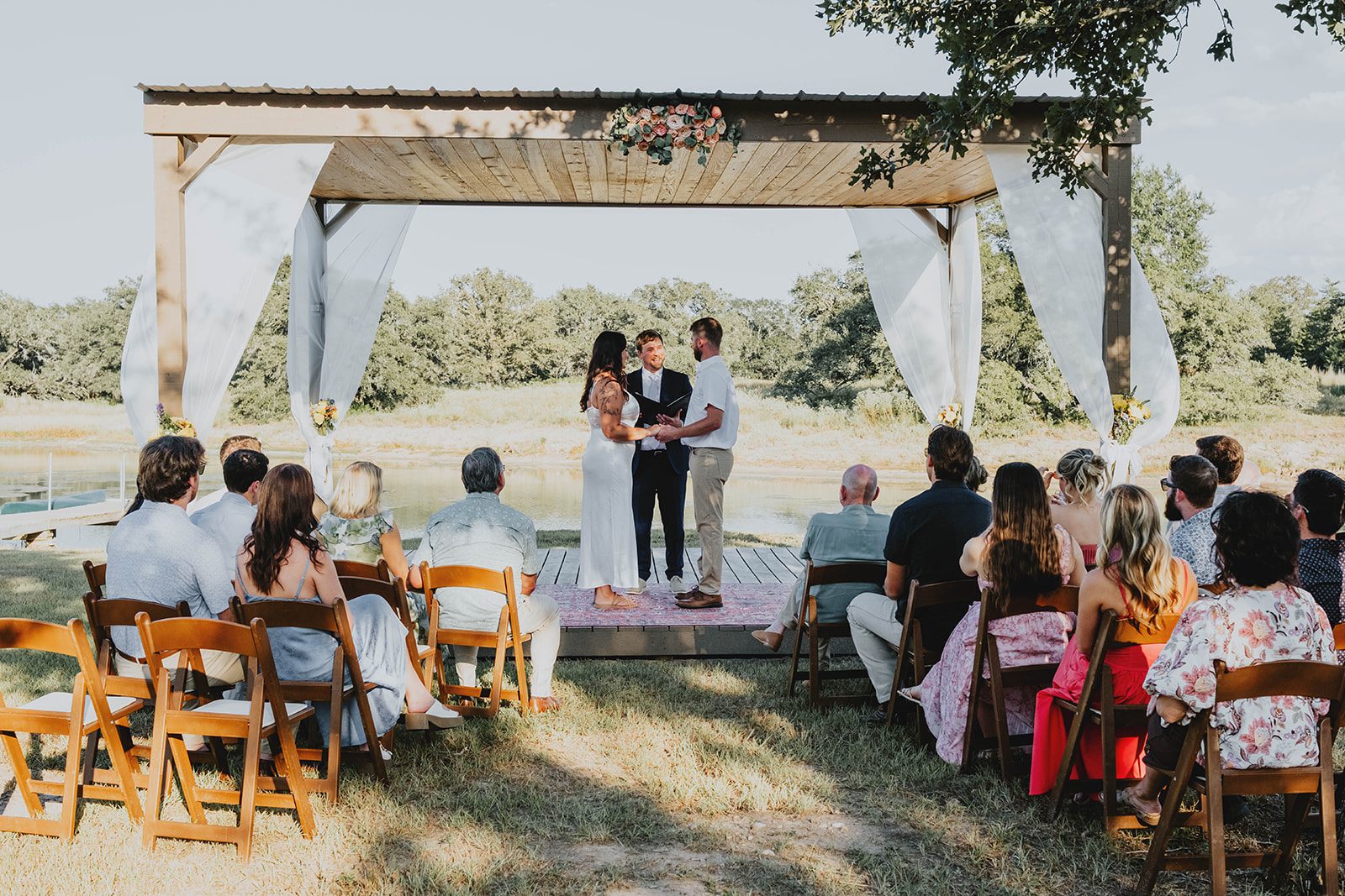 texas-backyard-rustic-austin-megan-kyle-p011-07 Guests watching the ceremony under the pergola at their Texas backyard wedding