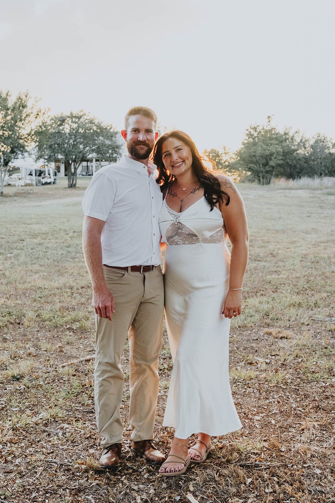 texas-backyard-rustic-austin-megan-kyle-p015-10 Newlyweds standing together in the open field at their Texas backyard wedding