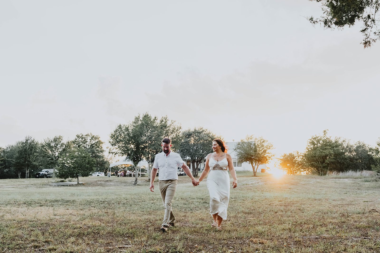 texas-backyard-rustic-austin-megan-kyle-p017-01 Couple walking toward the sunset, captured by Austin wedding photographers
