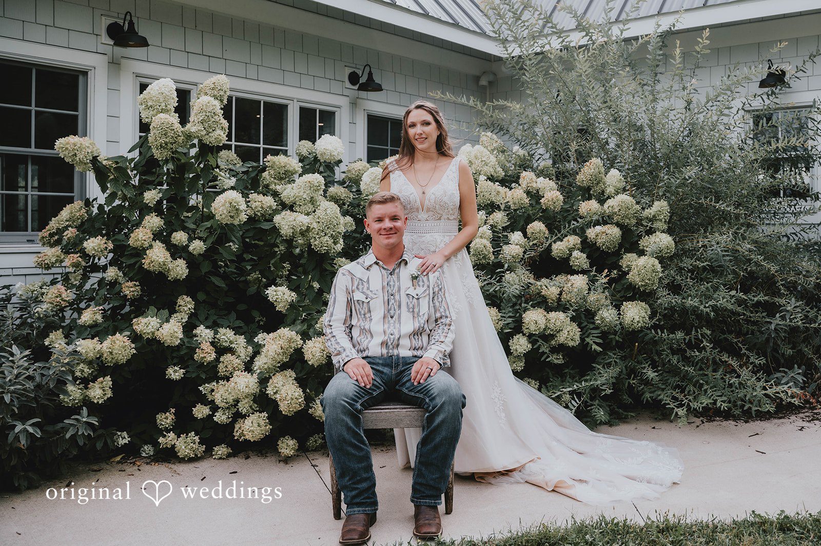 Groom seated with the bride by the hydrangeas