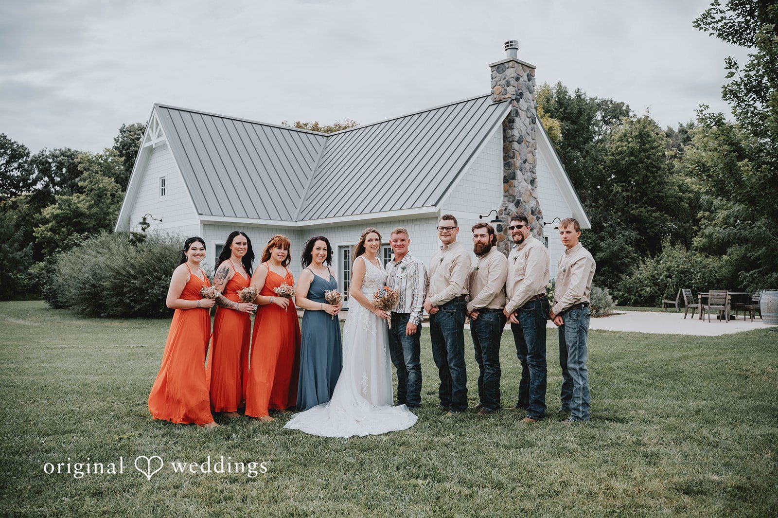 Couple with the wedding party by the farmhouse