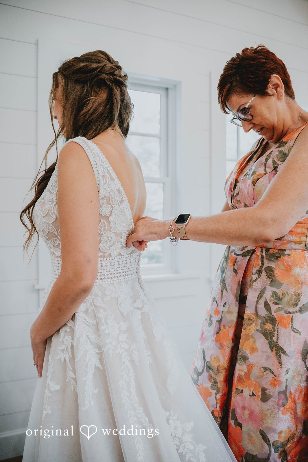 Mom helping the bride into her dress