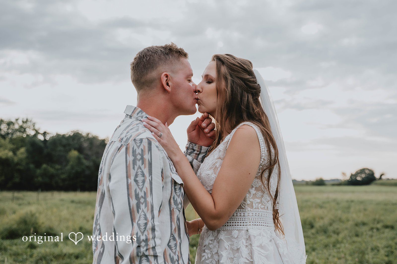 Couple kissing in the field at The Barn at Ballard Creek