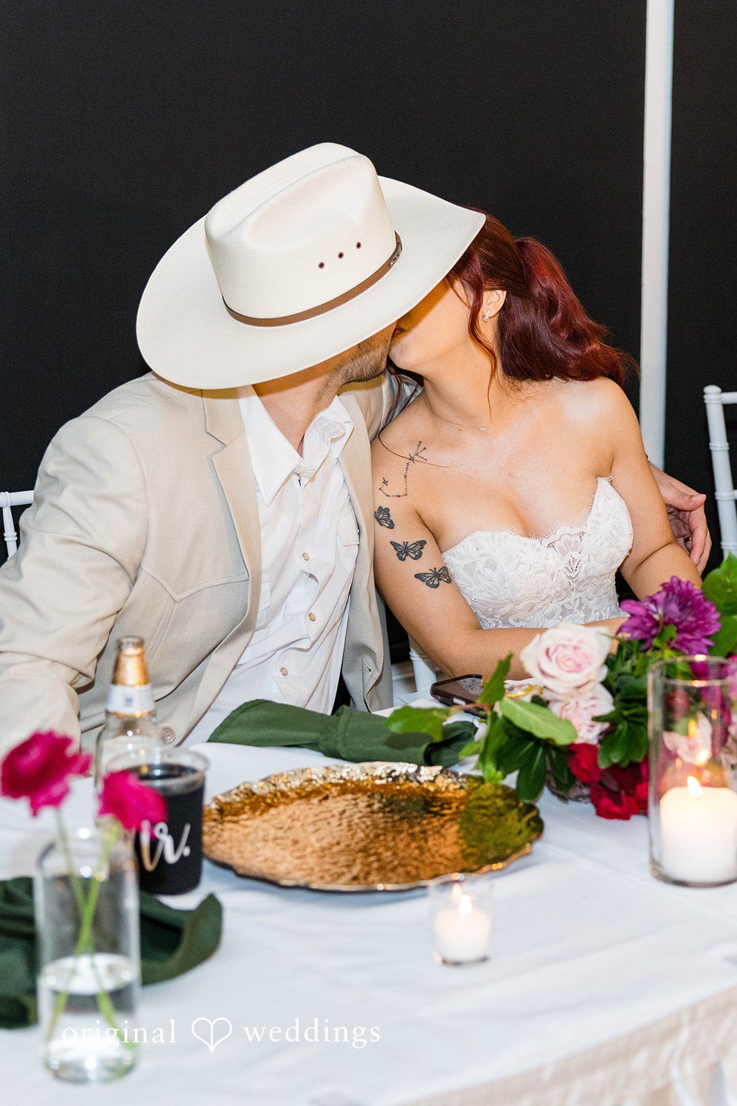Andrea + Roberto Groom in a cowboy hat kissing the bride at the table