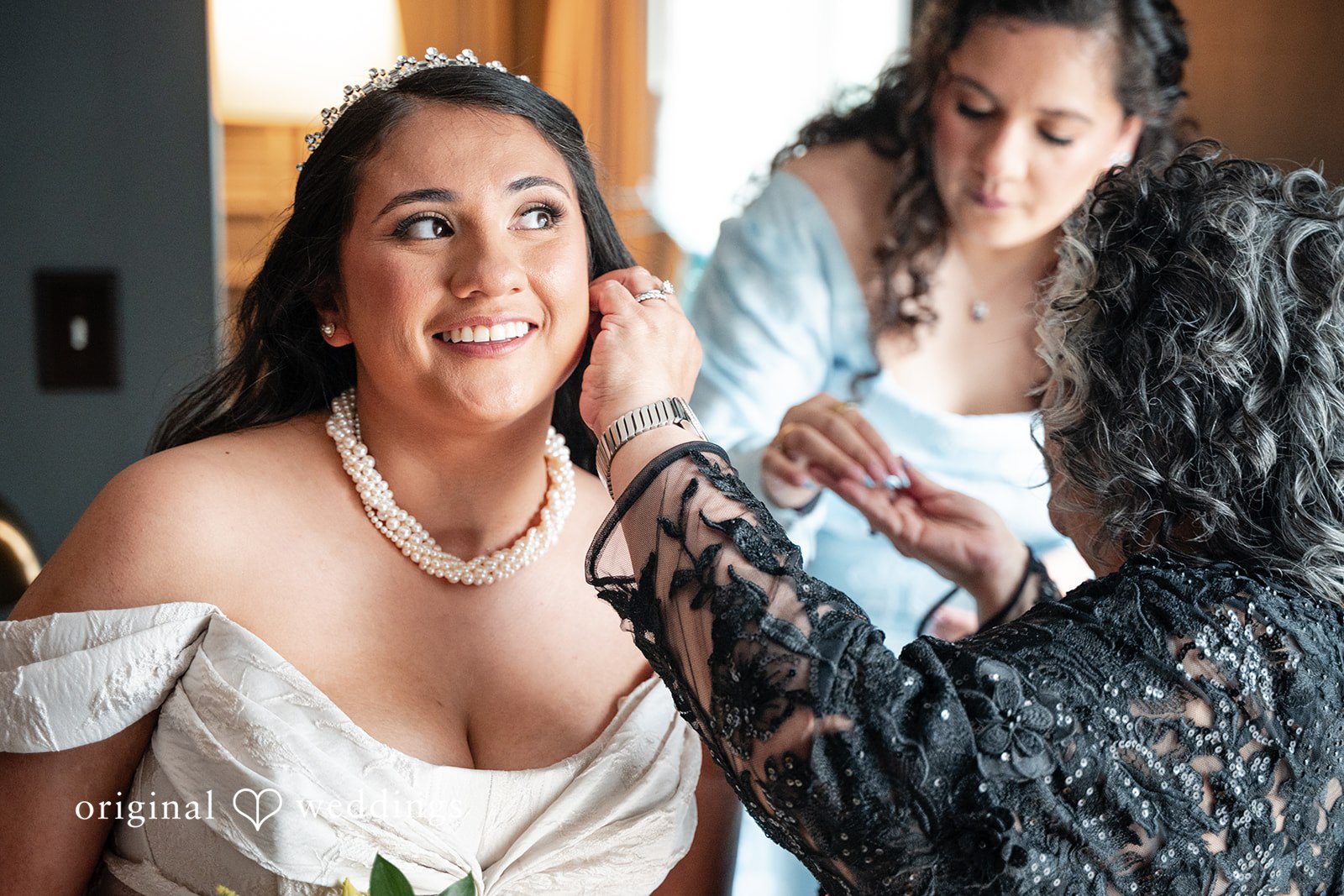 Selena + Ezequiel A woman looks down smiling as someone helps attach her necklace.