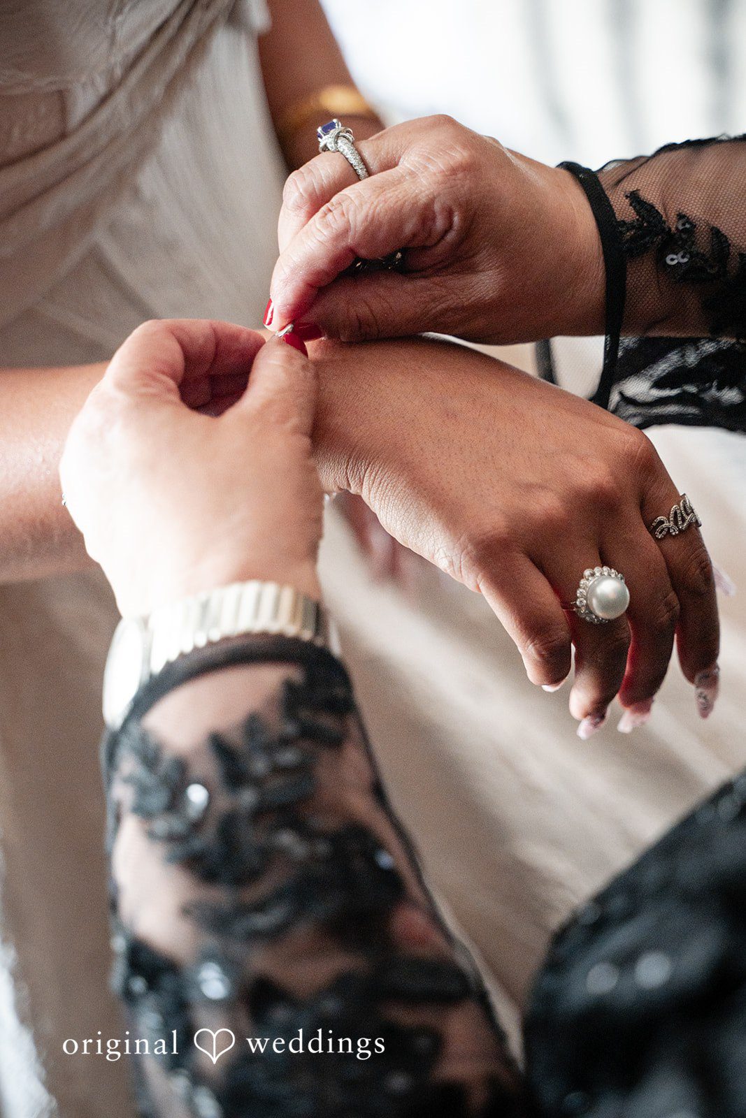 Selena + Ezequiel A close-up shot of a person's hands fastening a detailed bracelet onto a wrist.