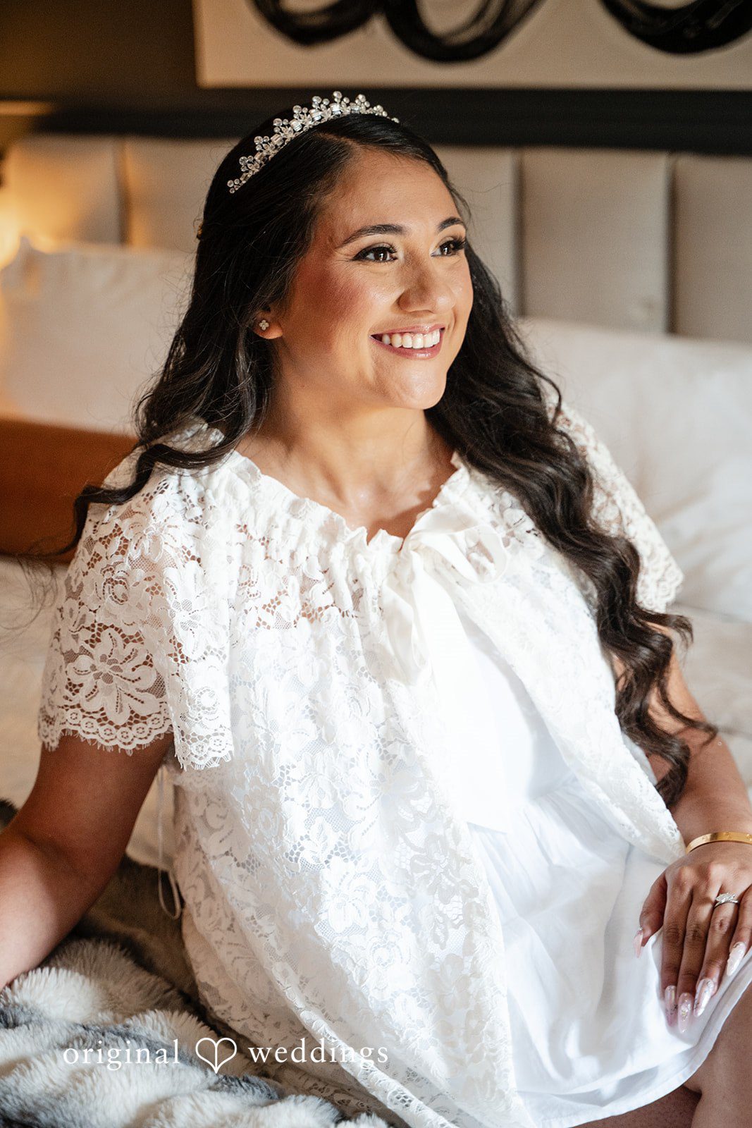 Selena + Ezequiel A portrait of a smiling woman with long dark hair wearing a white lace dress.