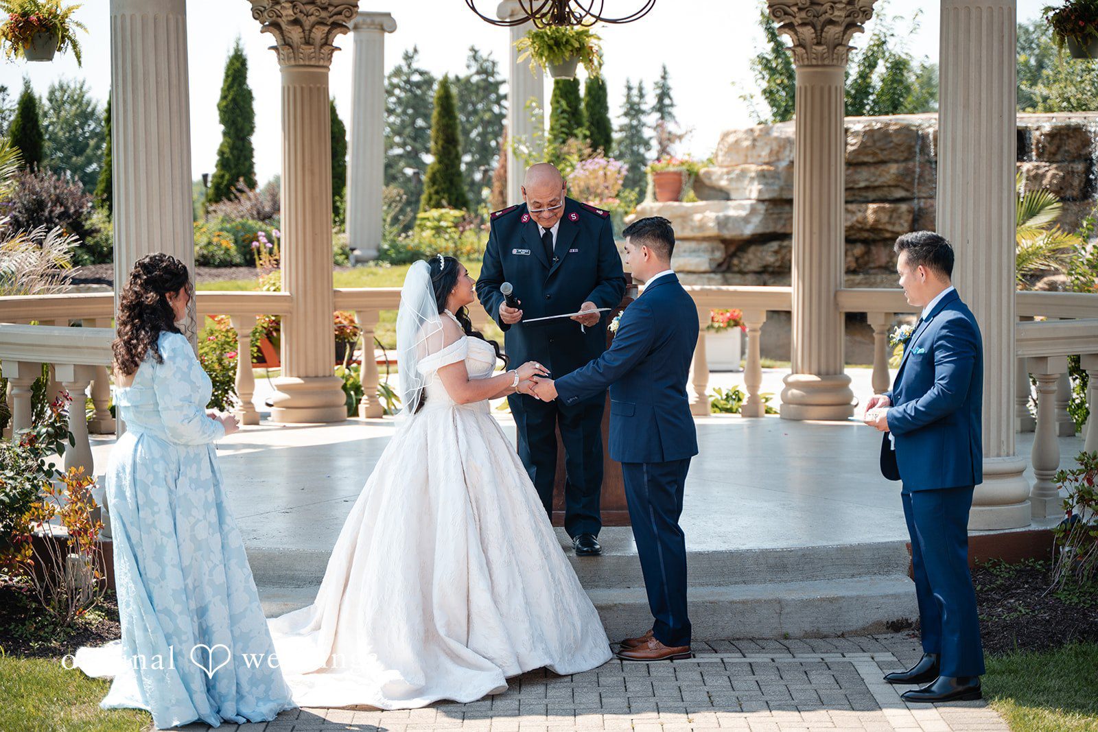 Selena + Ezequiel A bride and groom stand together holding hands at the altar during their ceremony.