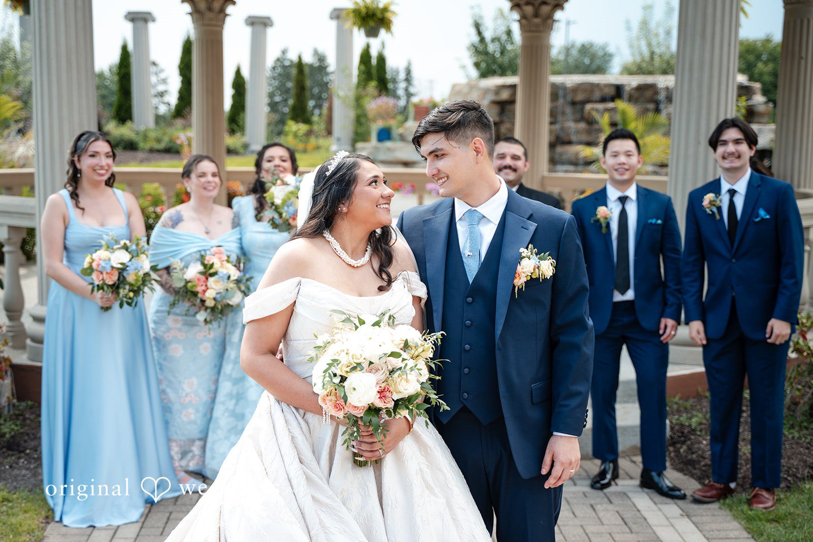 Selena + Ezequiel A bridal party poses together with bridesmaids in light-blue gowns and groomsmen in blue suits.