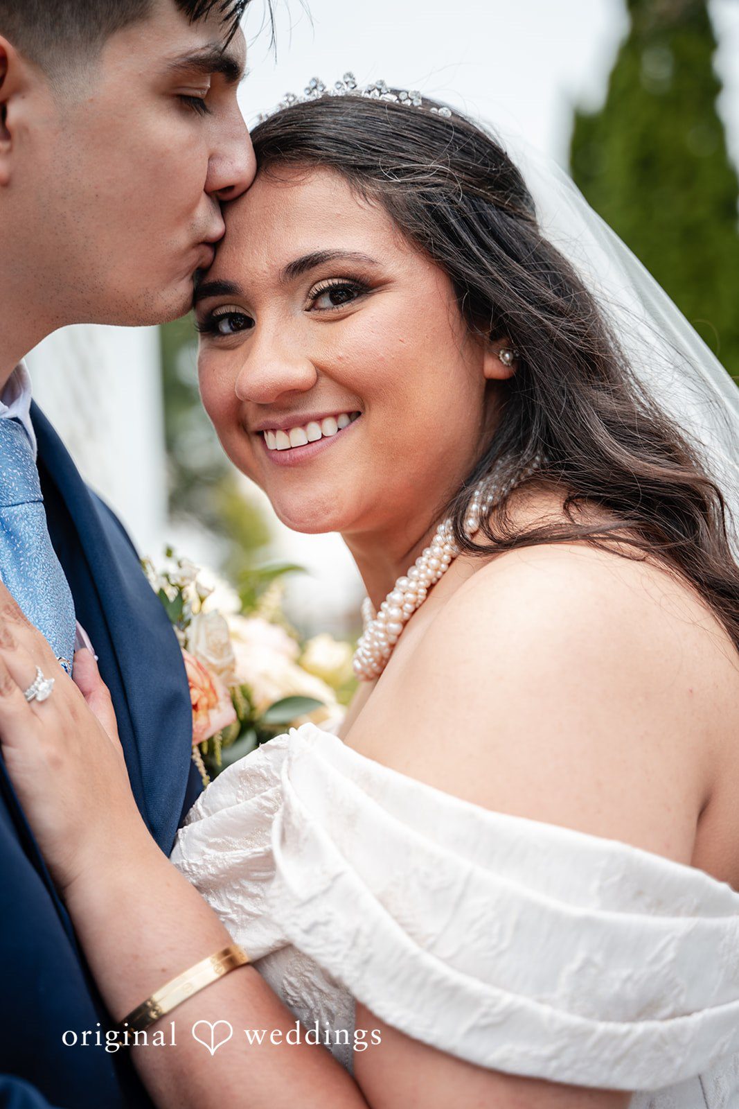 Selena + Ezequiel A close-up view of a smiling bride with long dark hair wearing a white gown.