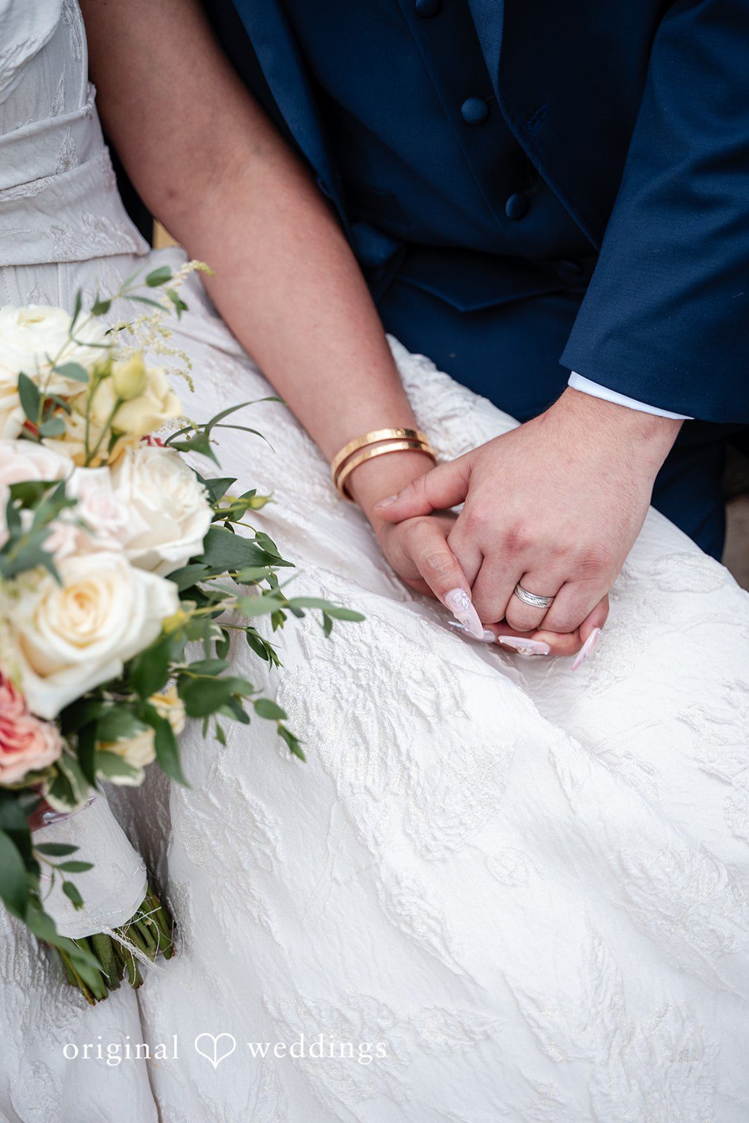 Selena + Ezequiel A close-up shot of a bride and groom holding hands while displaying their wedding bands.