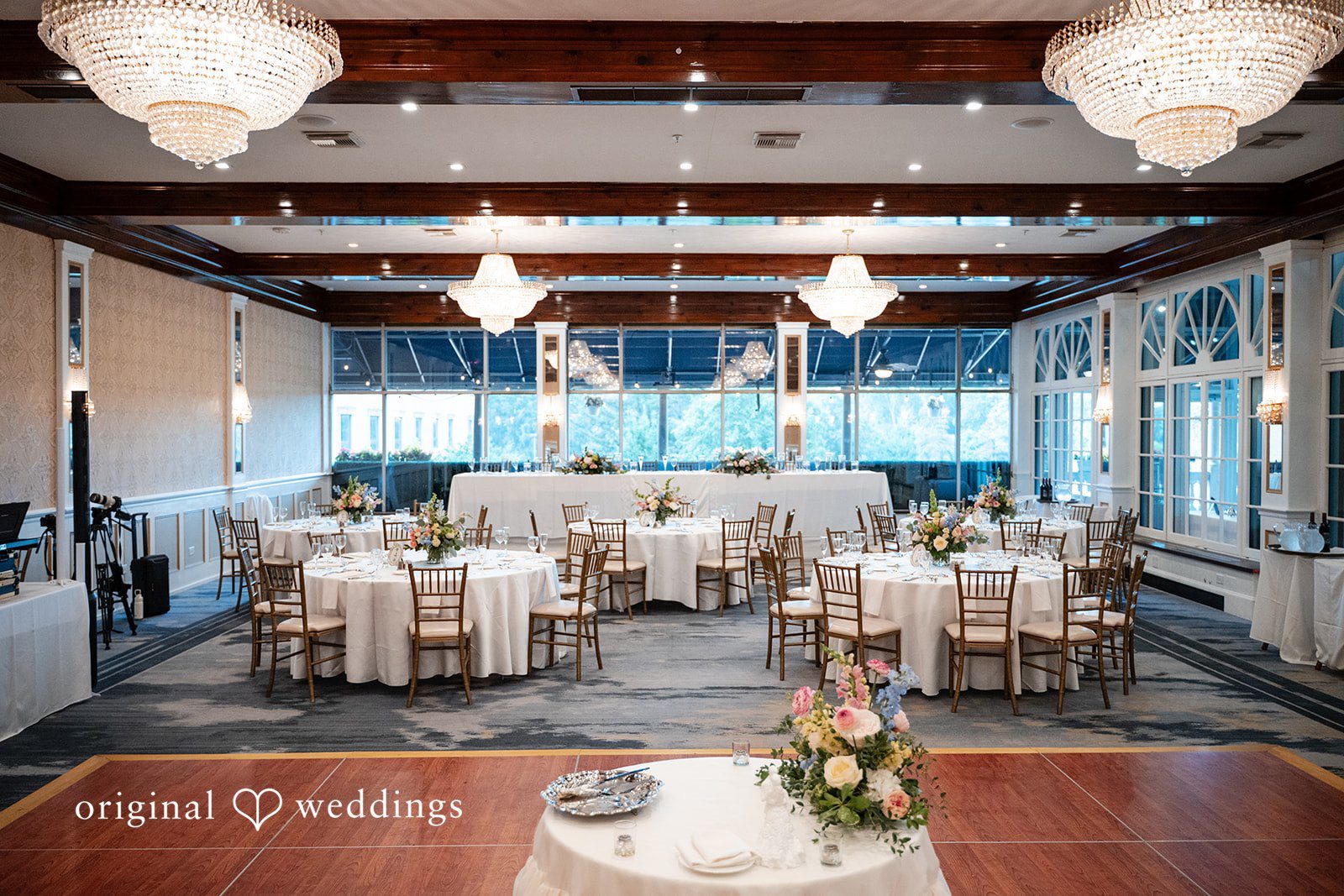 Selena + Ezequiel An empty reception room set up with decorated long guest tables and chairs.