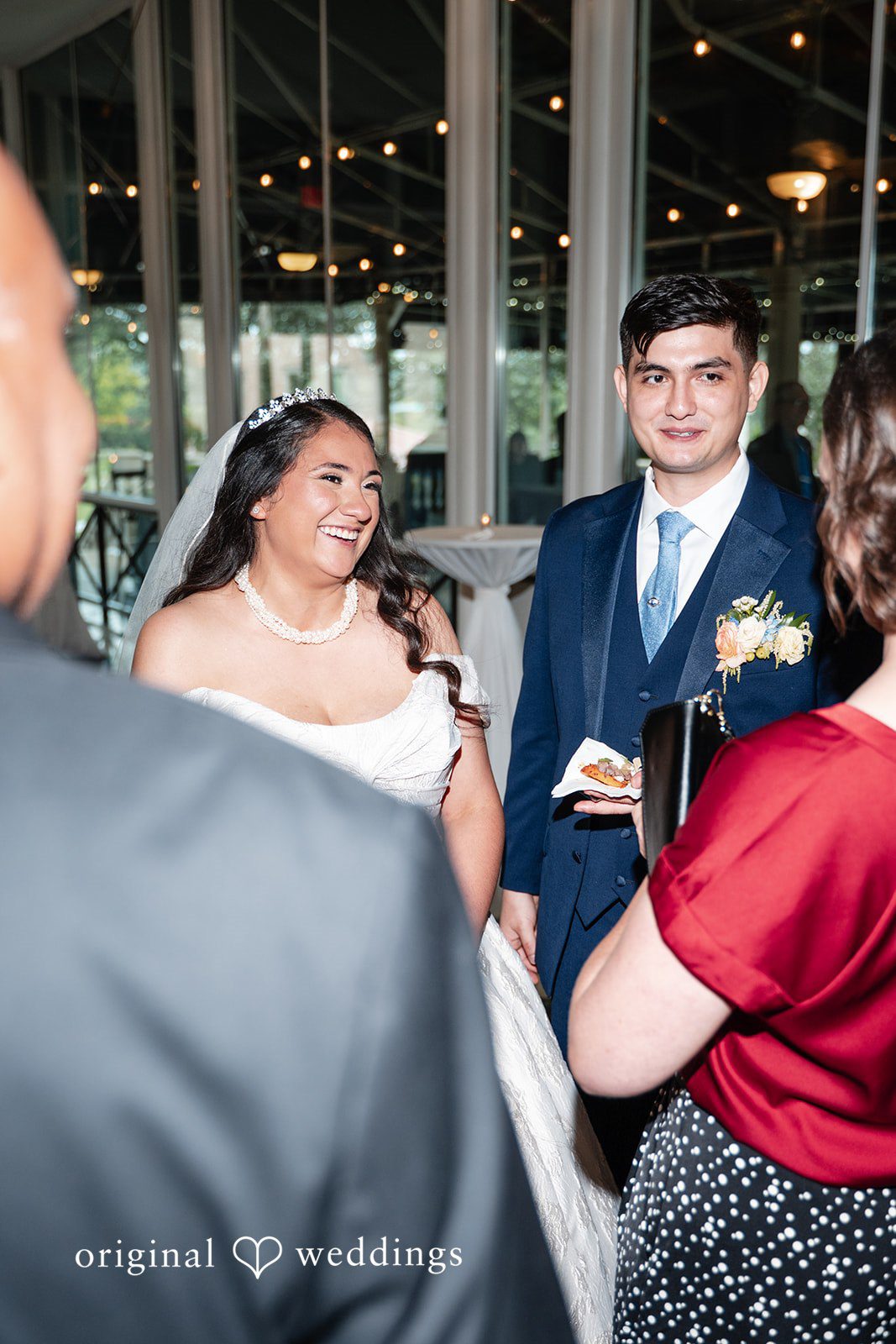 Selena + Ezequiel A bride and groom are captured in a candid moment chatting with guests at a reception table.