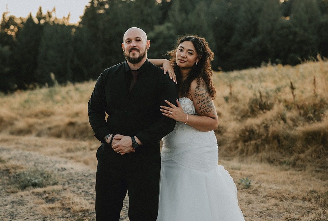 Alexis and Lucas smiling together in a golden field at sunset, captured by Portland wedding photographers from Original Weddings at The Empress Estate