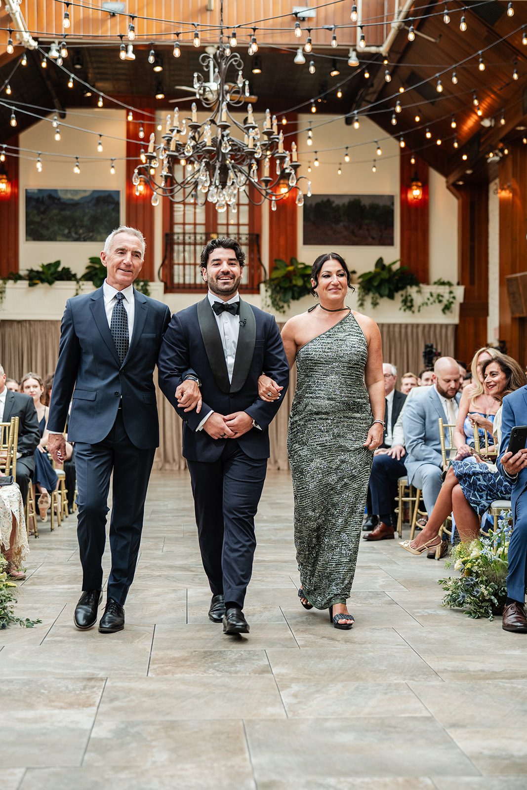 Groom walking down the aisle with his parents