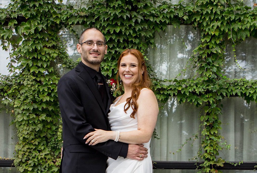 Stephanie and Charles smiling in front of an ivy covered wall, captured by Providence wedding photographers from Original Weddings at The Loom Hotel