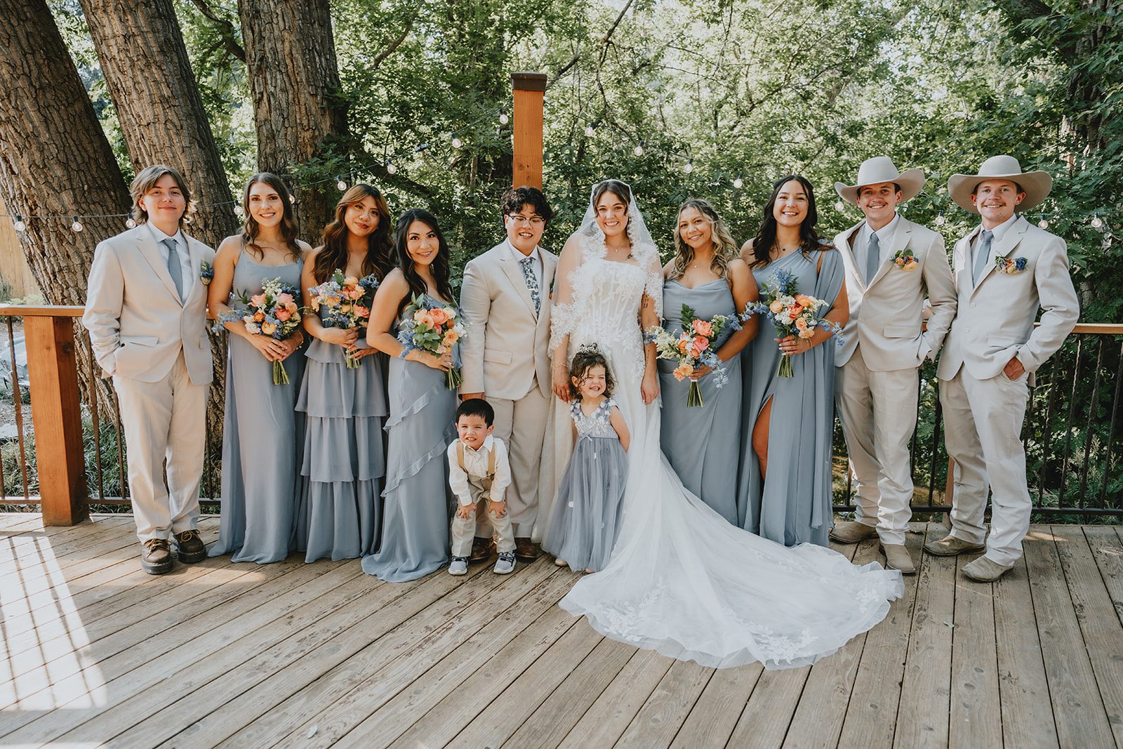 Full wedding party gathered under the trees at The Lyons Farmette