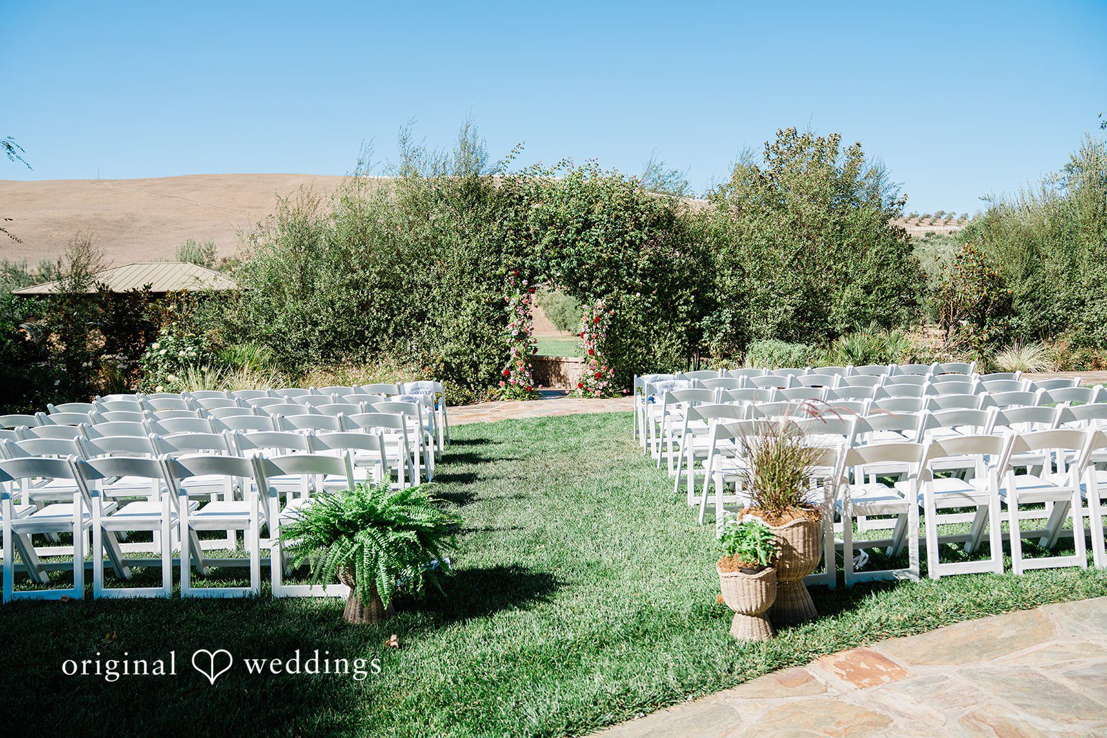 Savannah + Lucas White ceremony chairs set on the lawn at The Purple Orchid