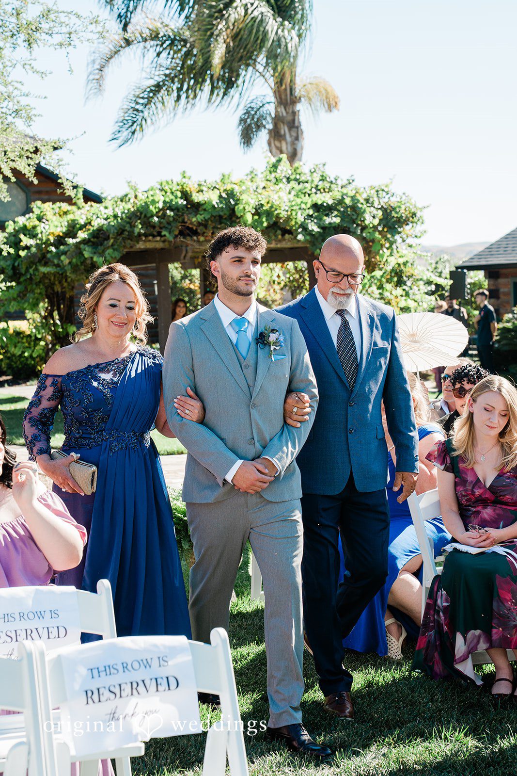 Savannah + Lucas Groom walking down the aisle with his family