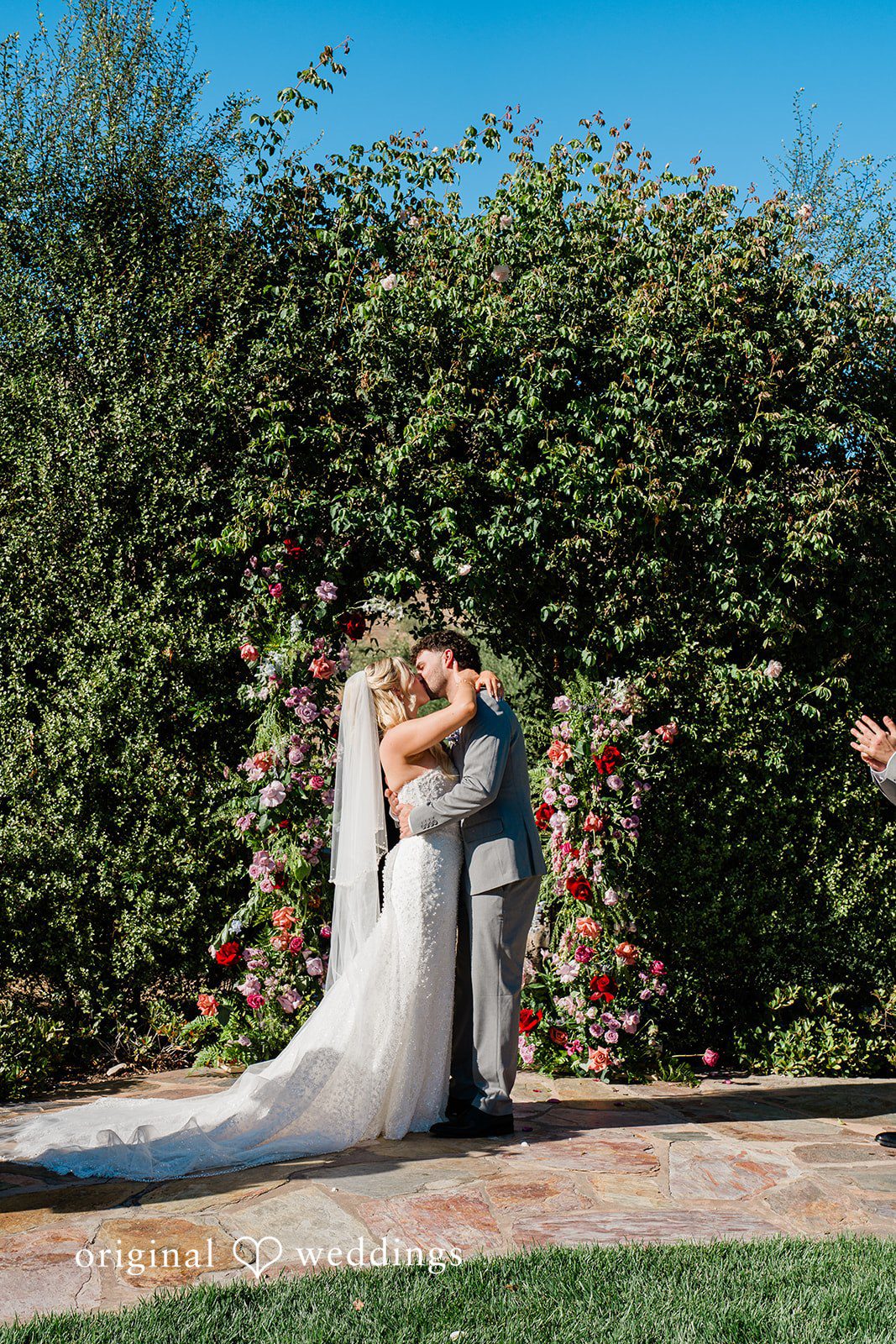 Savannah + Lucas Couple sharing a kiss by the green hedge
