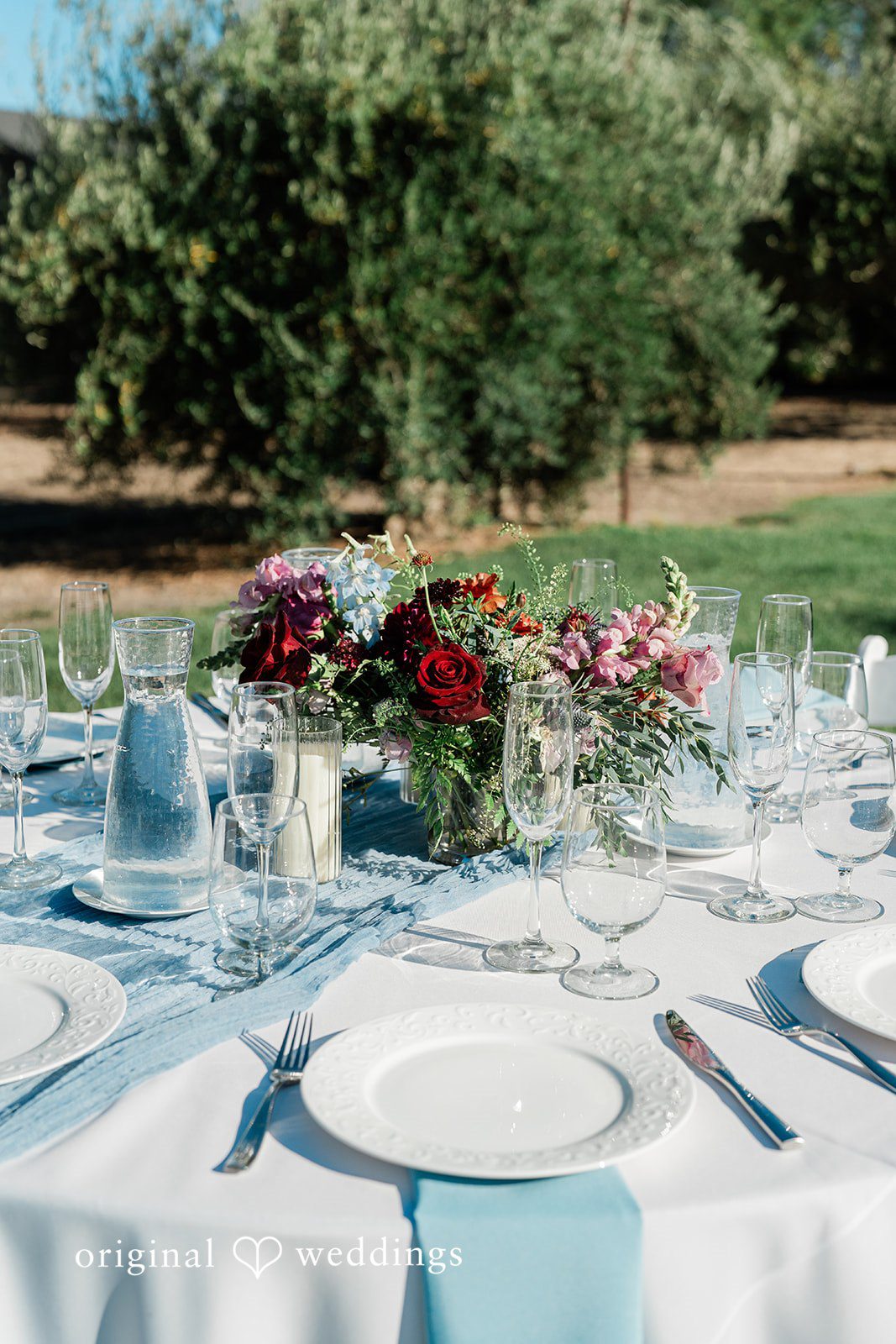 Savannah + Lucas Reception table set in blue with florals at The Purple Orchid