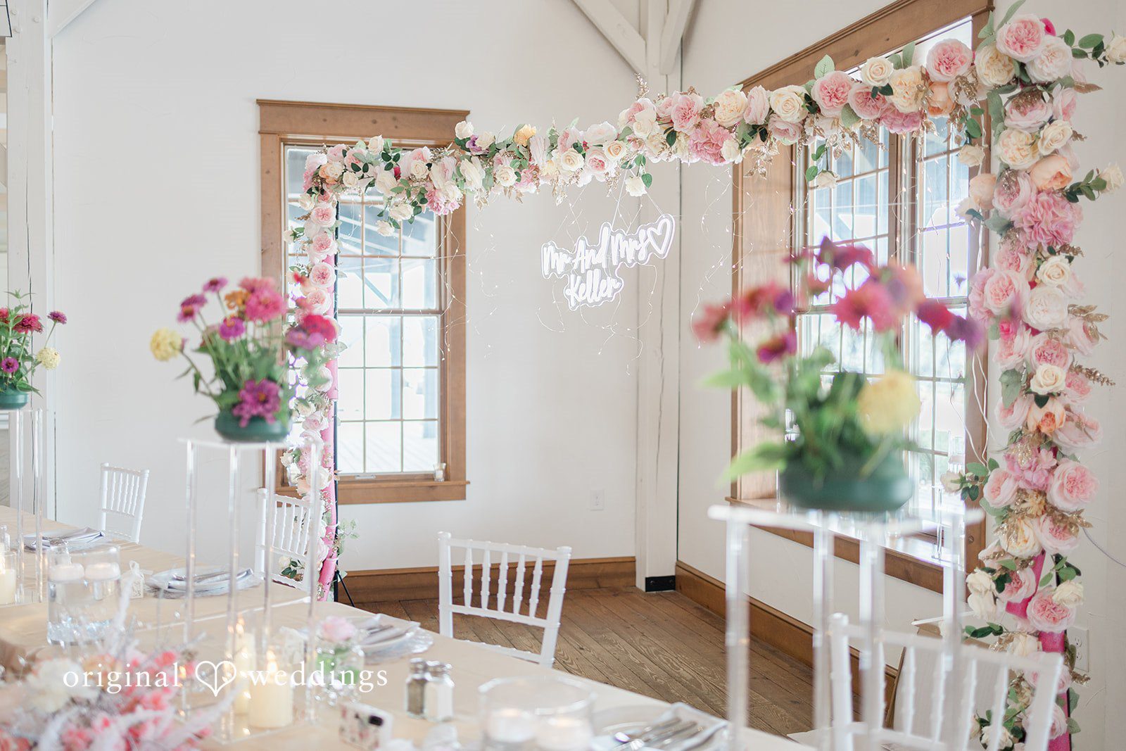 Daniel + Dalte A wedding reception space with tall, colorful floral pillars and small white tables.
