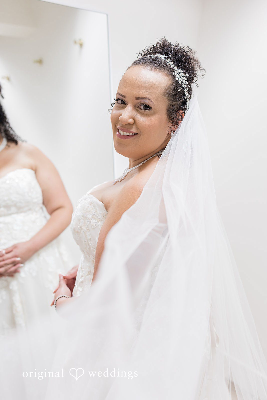 Daniel + Dalte A bride in a white wedding gown and veil smiles while looking to camera.