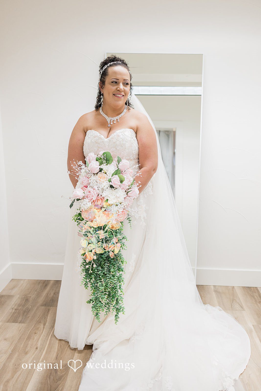 Daniel + Dalte A bride in a strapless white gown holds a large bouquet of pink and white flowers.