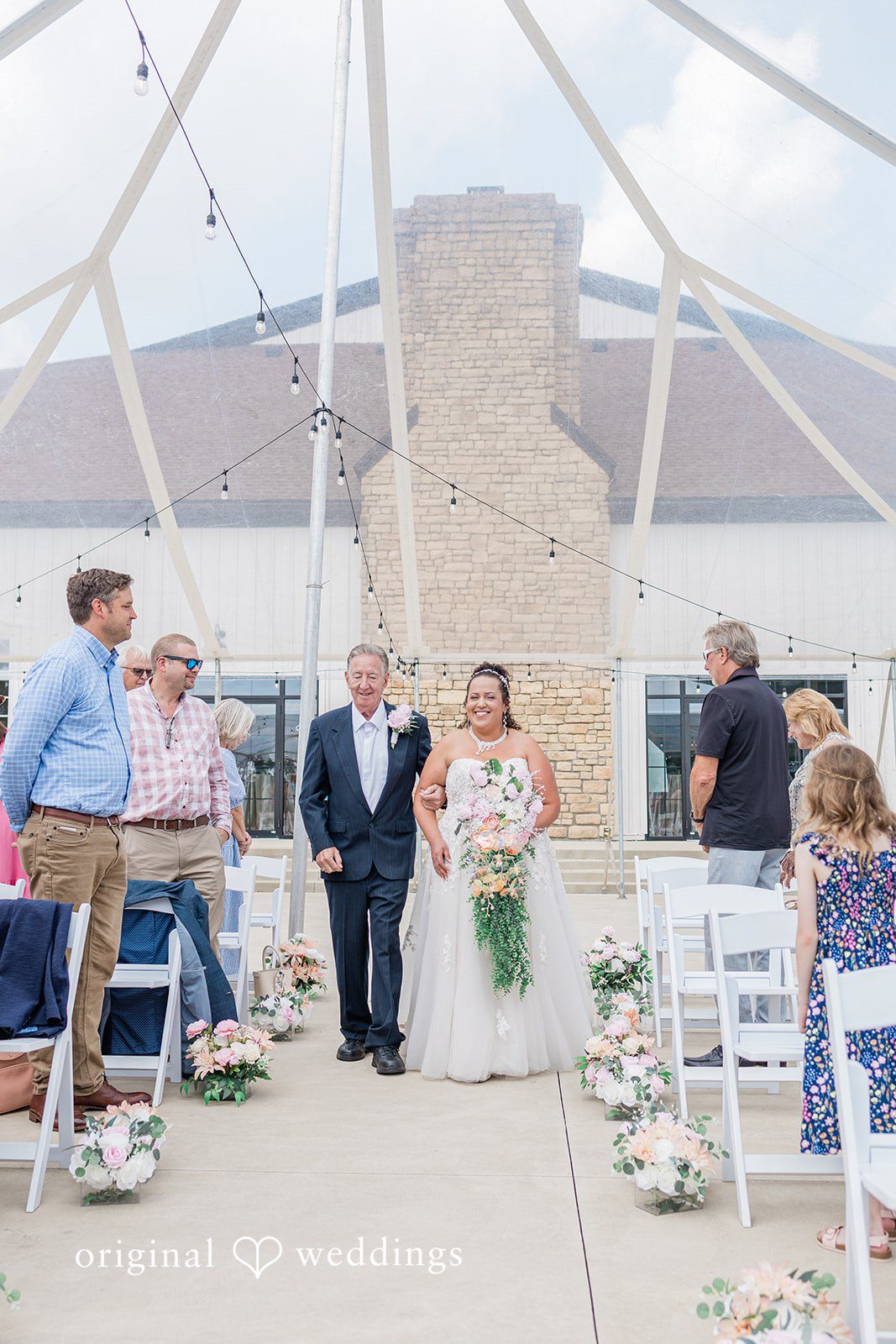 Daniel + Dalte Guests look on during a wedding ceremony held near a stone wall structure.