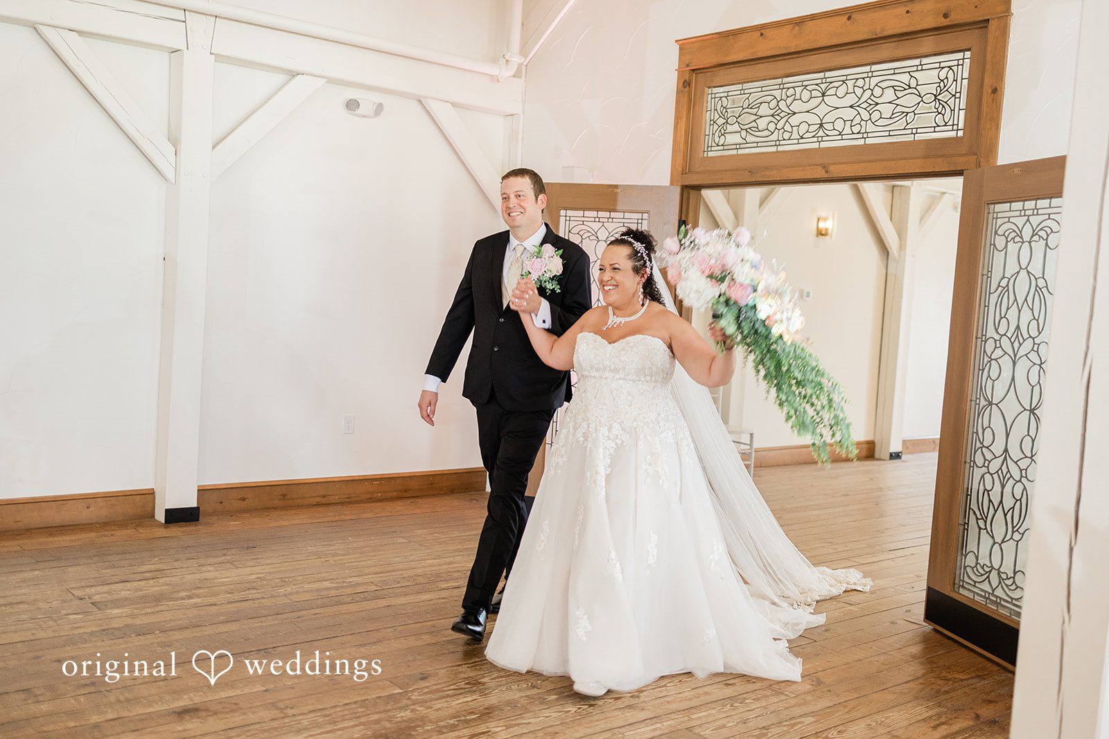 Daniel + Dalte A bride and groom walking together into a brightly lit reception hall.