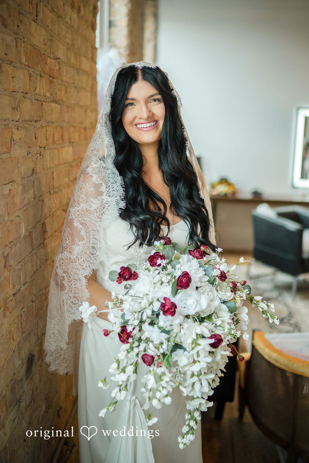 August 01, 2026 – Haley & Austin – (ID-4892) A bride holding a vibrant white and red bouquet while smiling directly at the camera.