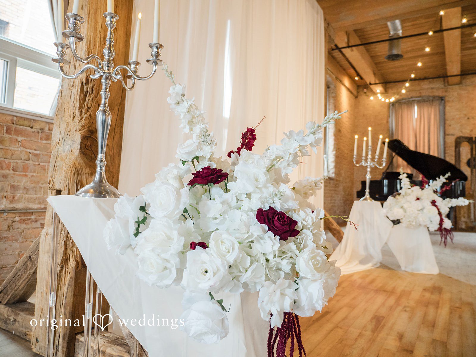 Haley + Austin A white floral arrangement with dark red accents placed on a wooden table decoration.