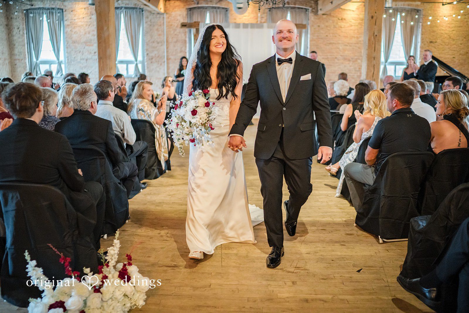 August 01, 2026 – Haley & Austin – (ID-4892) A newly married bride and groom smiling while walking down the aisle together.
