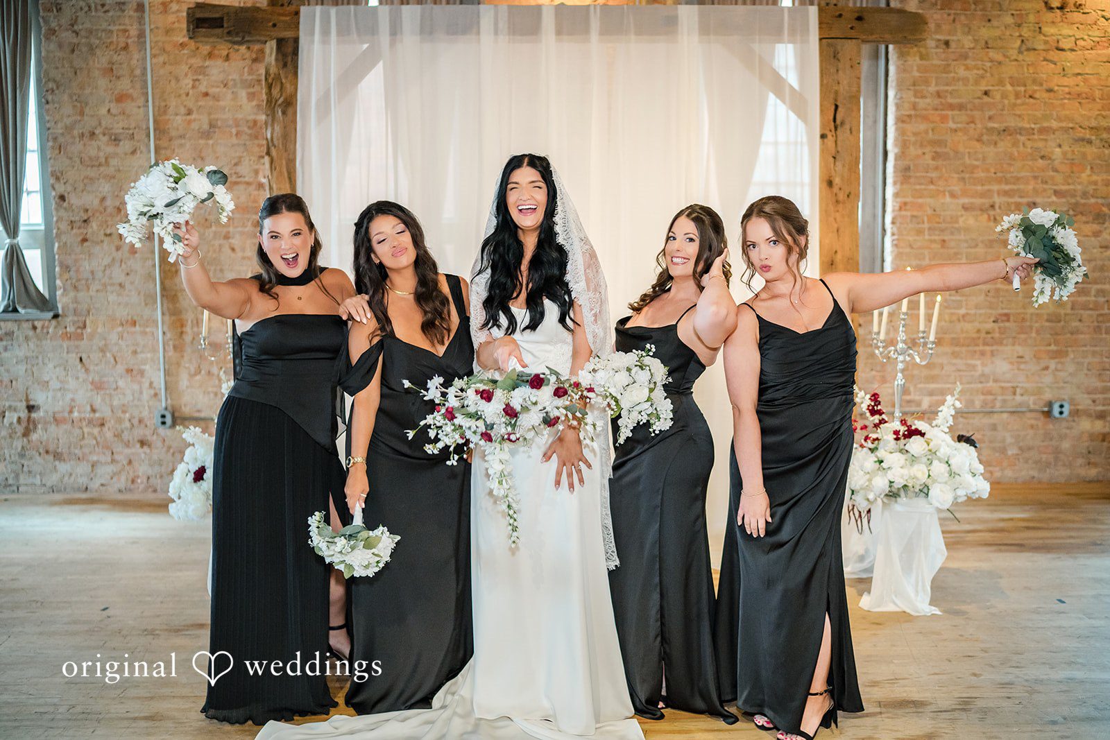 August 01, 2026 – Haley & Austin – (ID-4892) A group of bridesmaids in sleek black dresses raising their bouquets in celebration.