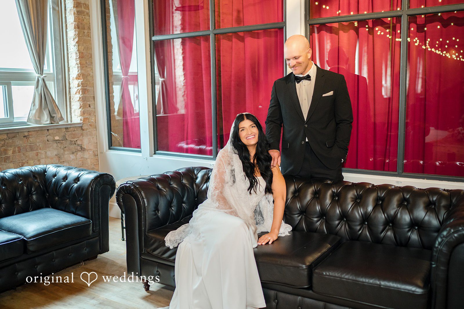 August 01, 2026 – Haley & Austin – (ID-4892) A bride sitting on a black leather couch next to a groom standing behind her.
