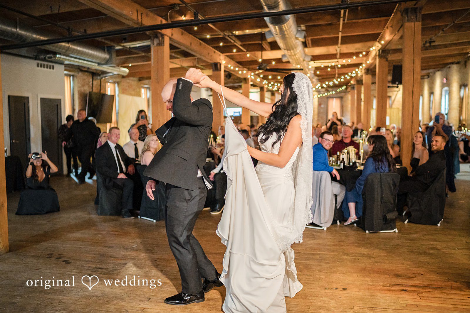 August 01, 2026 – Haley & Austin – (ID-4892) A bride and groom dancing and raising their hands joyfully surrounded by guests at a wedding reception.
