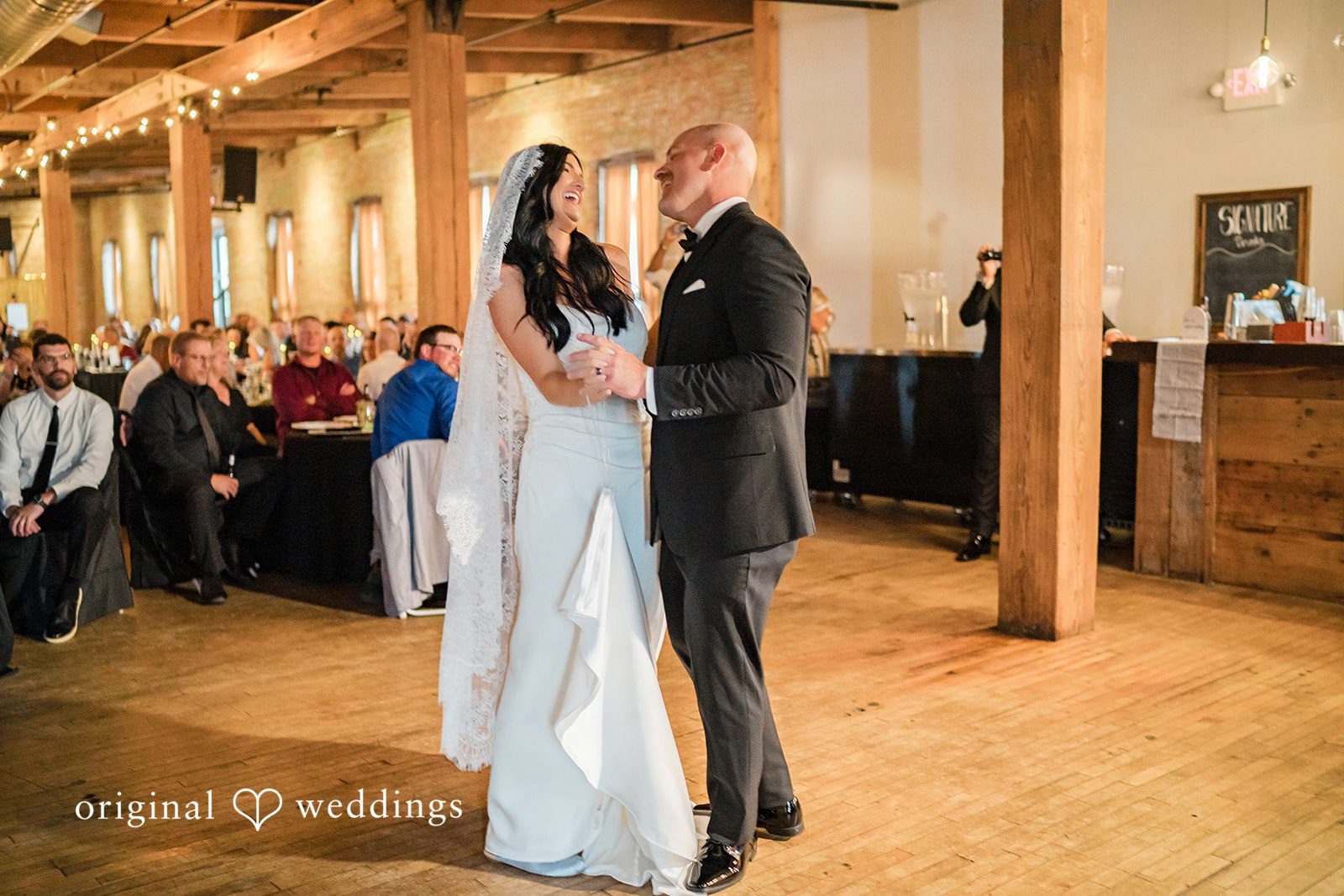 August 01, 2026 – Haley & Austin – (ID-4892) A bride and groom holding hands while smiling at each other on a wooden dance floor.