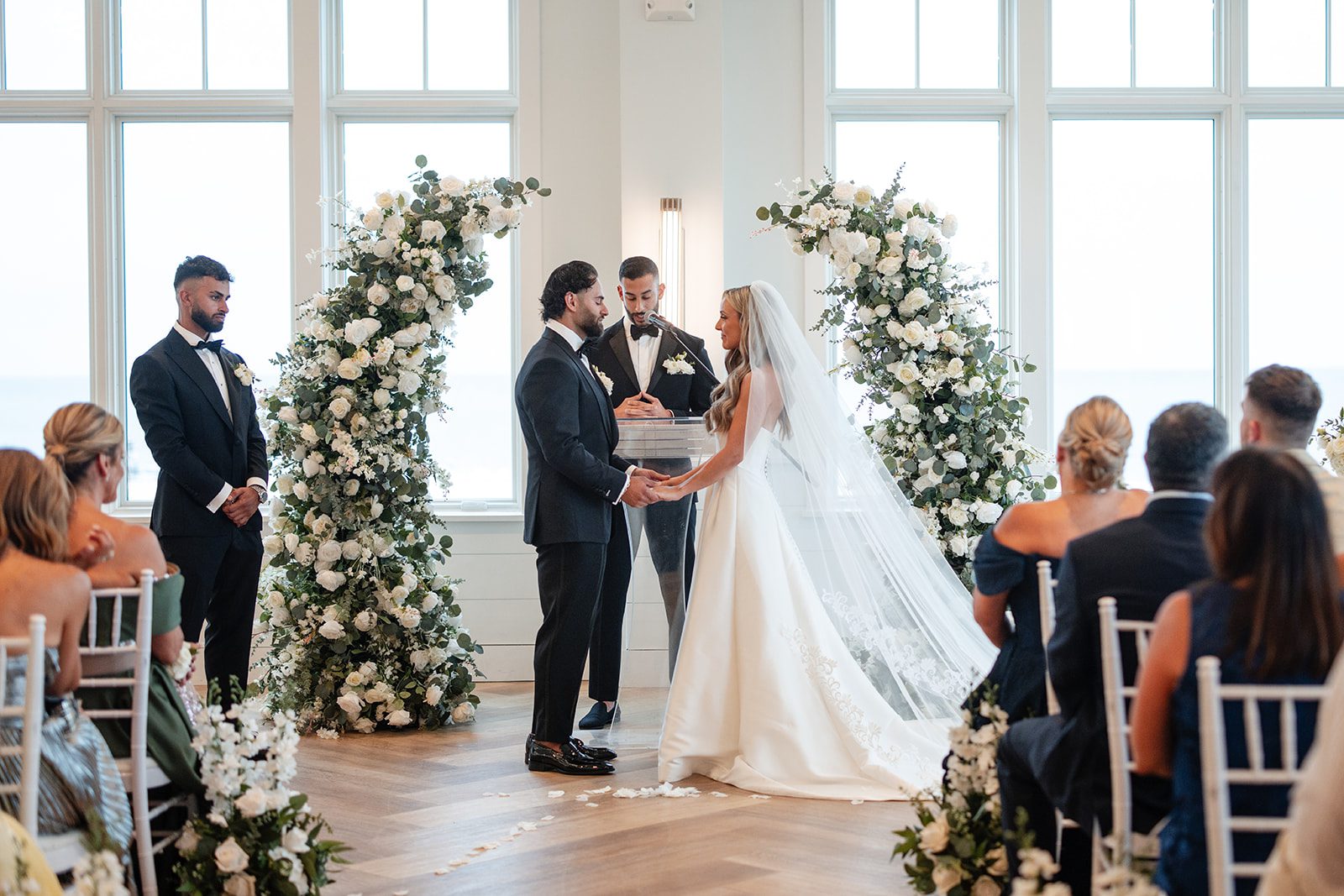 Guests watching the bride arrive at the floral arch