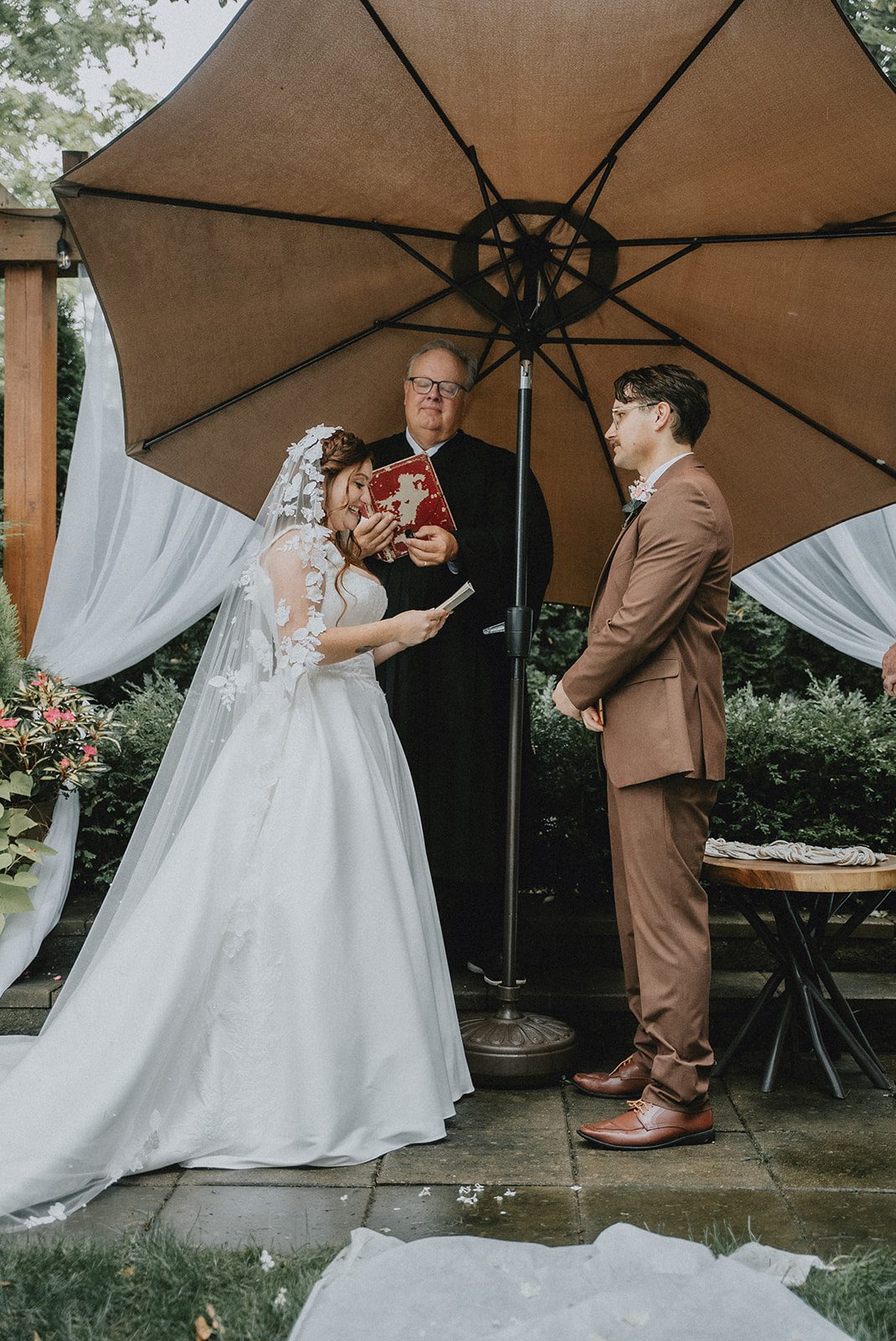 Couple under umbrellas during the ceremony